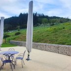 une grande terrasse avec du mobilier de jardin donne sur un pré avec des collines en arrièreplan
