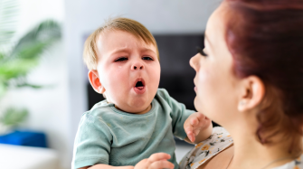 Bébé ayant une quinte de toux dans les bras de sa mère