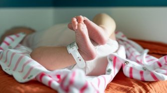 un nourisson est couché, l'image montre ses petits pieds avec le bracelet de la maternité