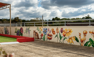 de grandes fleurs et un chat sont peints sur le mur qui longe une grande terrasse