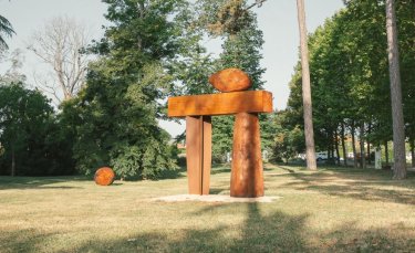 dans un parc, une grande sculpture en bois à la forme d'une porte