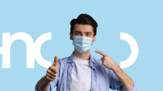 un homme portant un masque chirurgical lève le pouce en signe de satisfaction