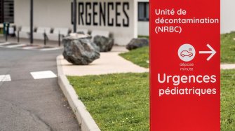 le long d'une route, un panneau de signalisation indique la direction à prendre pour accéder aux urgences pédiatriques