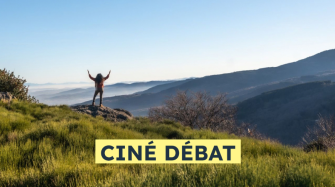 dans un paysage de moyenne montagne une personne seule est debout les bras levés vers le ciel