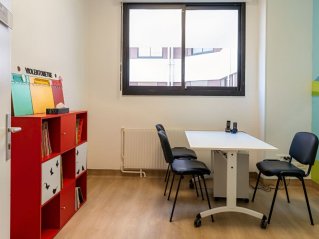 une pièce avec une fenetre, une table et des chaises, des étagères rouges et un mur décoré
