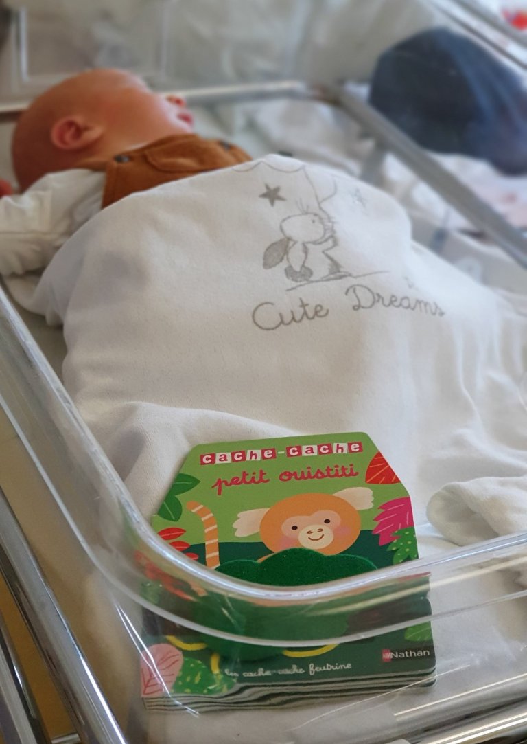 Nouveau né à la maternité des HNO, avec son livre doudou offert dans la cadre de l'opération prévention "1 bébé, 1 livre"