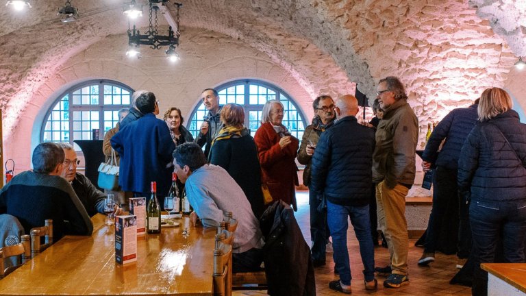 un groupe de personnes discutent en dégustant du vin