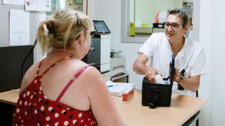 Dr Rémi Vial, pharmacien aux Hôpitaux Nord-Ouest, rétrocédant une boite de médicaments à une patiente