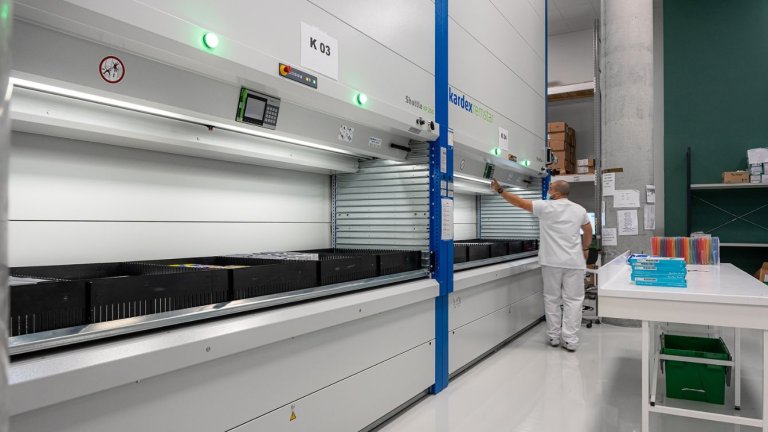 un professionnel de santé travaille devant des robots de stockage de médicaments