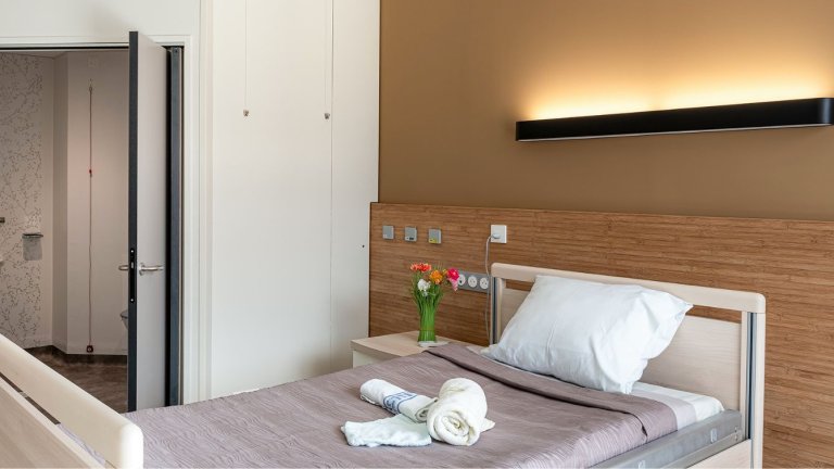 une cambre avec un lit, une grande tête de lit bois clair, un bouquet de fleurs sur la table de lit