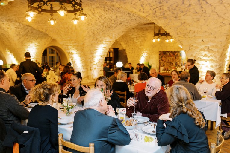 dans une ambiance chaleureuse, des personnes sont attablées dans une vaste salle voutée