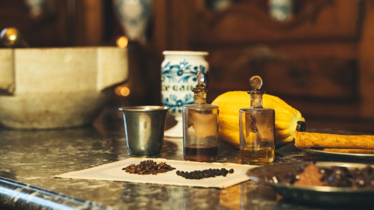 des épices, du chocolat et des pettes fioles en verre sont posés sur une surface de marbre noir