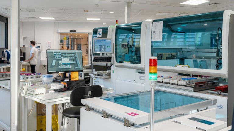 dans une vaste pièce lumineuse, des automates aux surfaces bleutée 