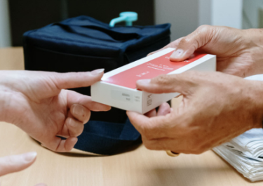 pharmacien rétrocédant une boite de médicament à un patient